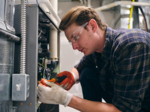 A furnace repairman working inside a home, repairing a furnace.