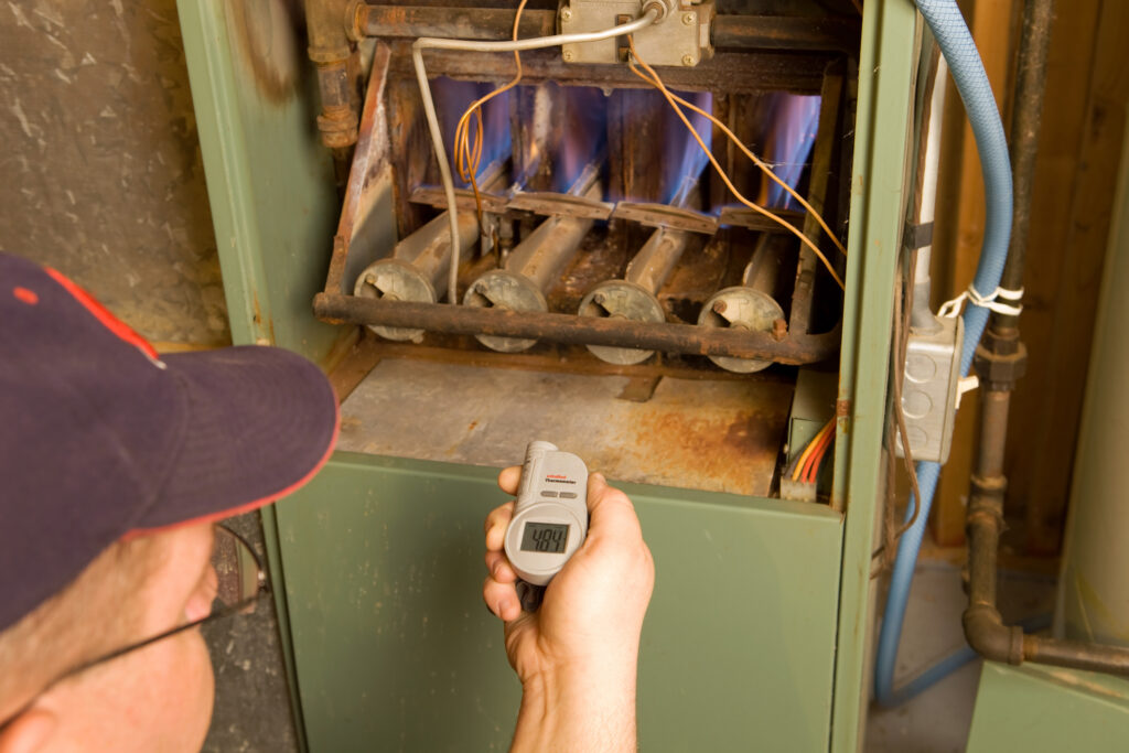 furnace repairman using infrared thermometer to test furnace
