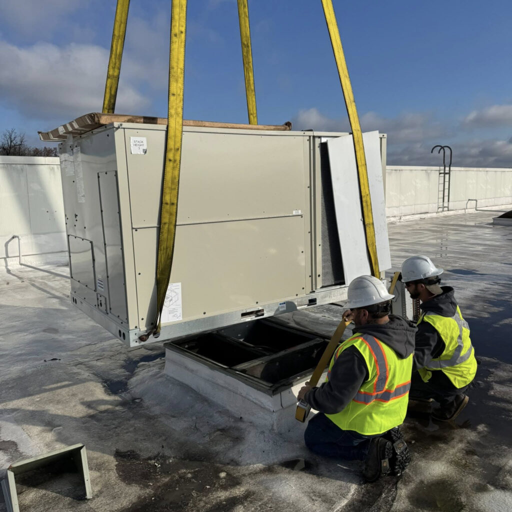 closeup of Ventec's commercial HVAC technicians positioning a large rooftop hvac unit on customers roof